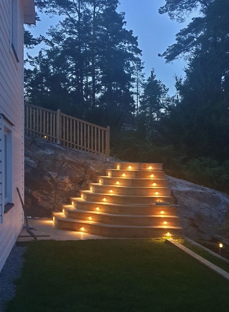 Trappa i trä med inbyggd belysning i stegen upp mot berget i Strömma i kvällsljus